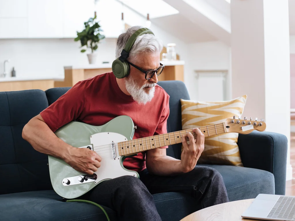 homme qui joue de la guitare électrique avec un casque